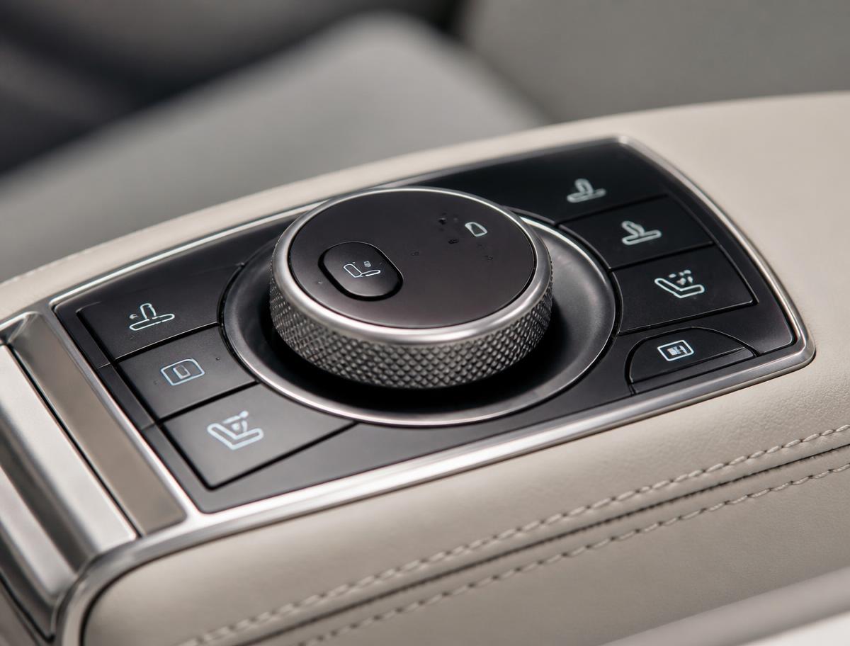 Close-up of a knurled control dial and backlit buttons set into a leather armrest